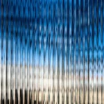 A blurred reflection of a bright blue sky and clouds creates a wavy, textured pattern, enhancing the sense of depth.