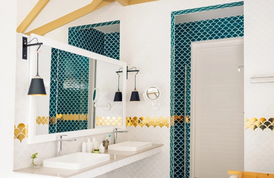 A modern bathroom featuring a large mirror, dual sinks, and decorative blue and gold tile accents, creating an elegant ambiance.