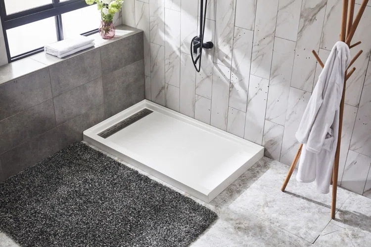 A modern bathroom featuring a sleek shower area with a white shower base, a gray rug, and a wooden towel rack holding a robe.
