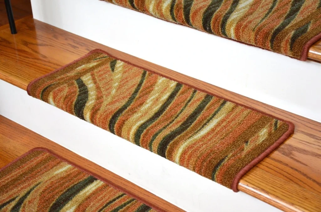 Close-up of wooden stairs with brown, orange, and green striped carpet treads for added grip and decoration.