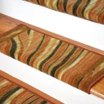 Close-up of wooden stairs with brown, orange, and green striped carpet treads for added grip and decoration.