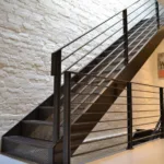 Modern black metal staircase with perforated steps and railings against a white brick wall in a minimalist interior.